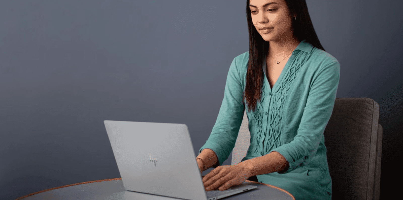 Joven mujer trabajando en un portátil HP en un entorno de oficina moderna