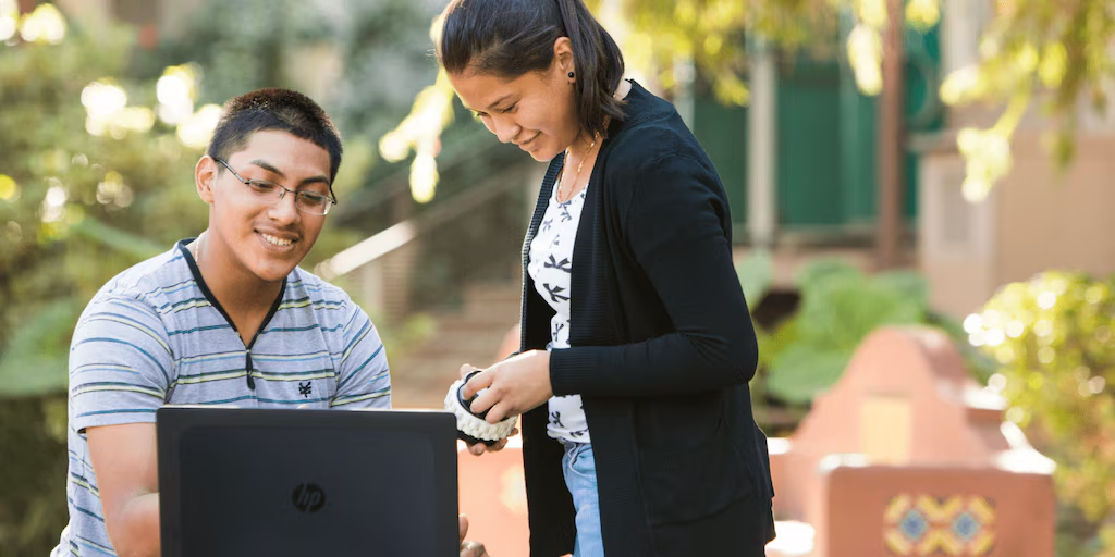 Estudiantes colaborando al aire libre con una laptop HP